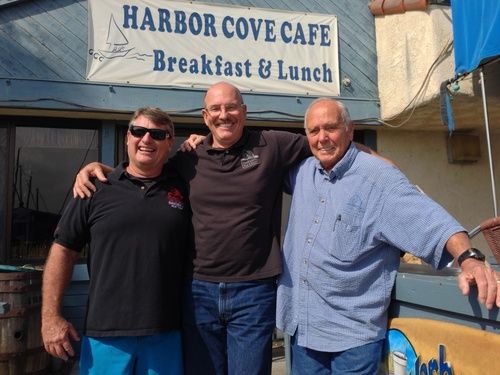 Three men smiling in front of Harbor Cove Cafe